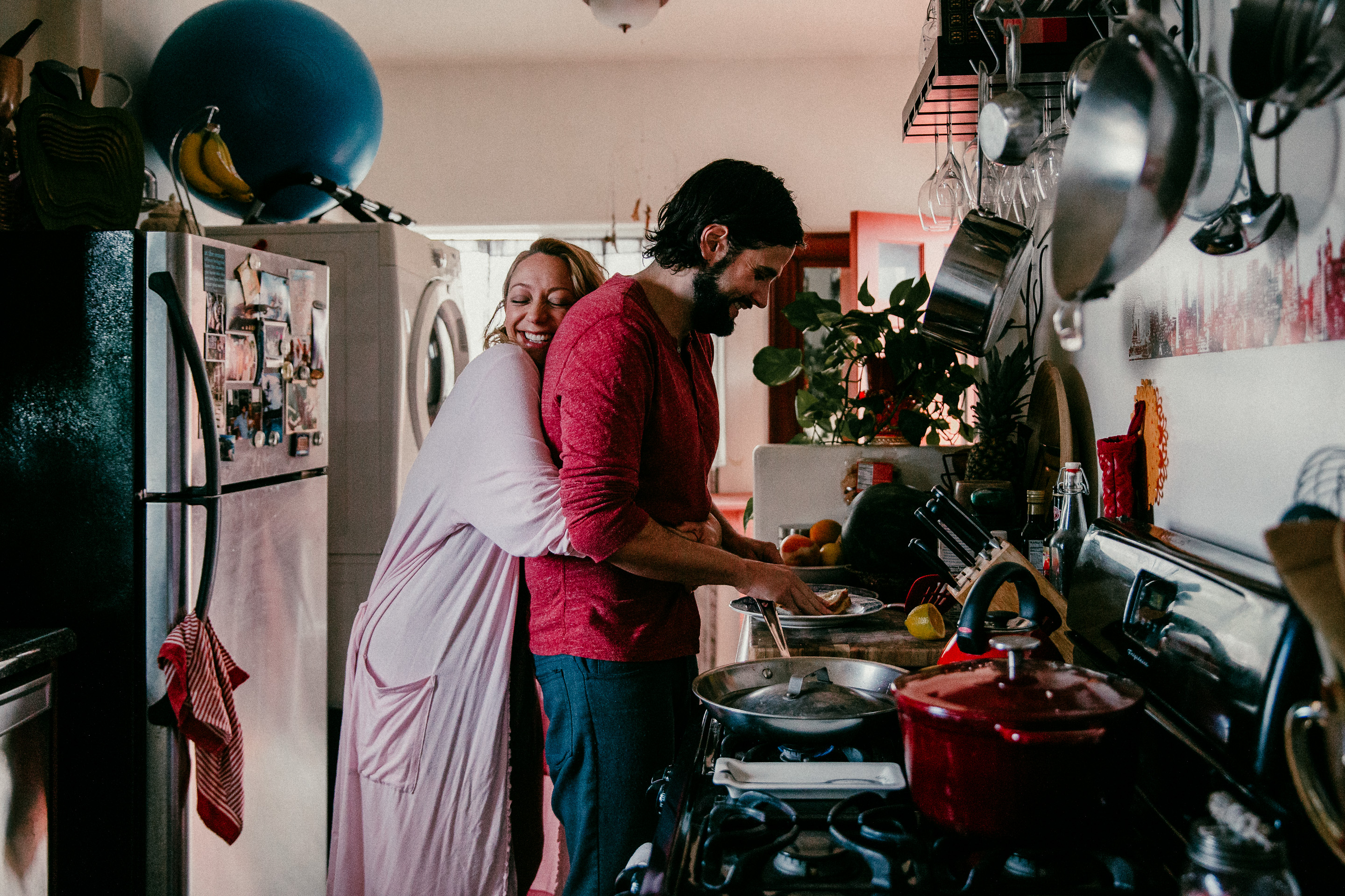 Pregnant wife hugging husband in the kitchen, Echo Park, Los Angeles, CA