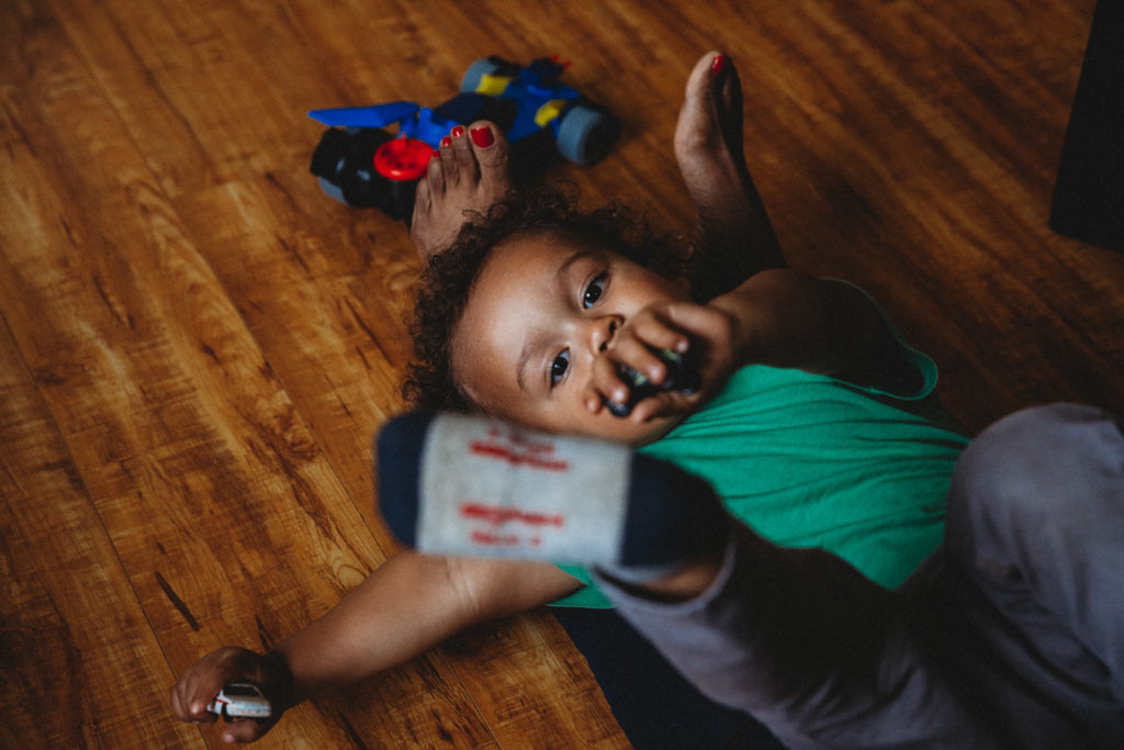 Toddler laying on floor with hand and foot in the air