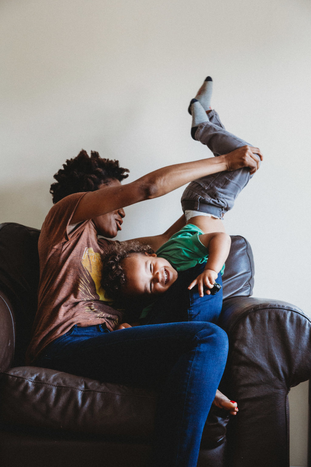 Mom holding toddler upside down on chair in living room