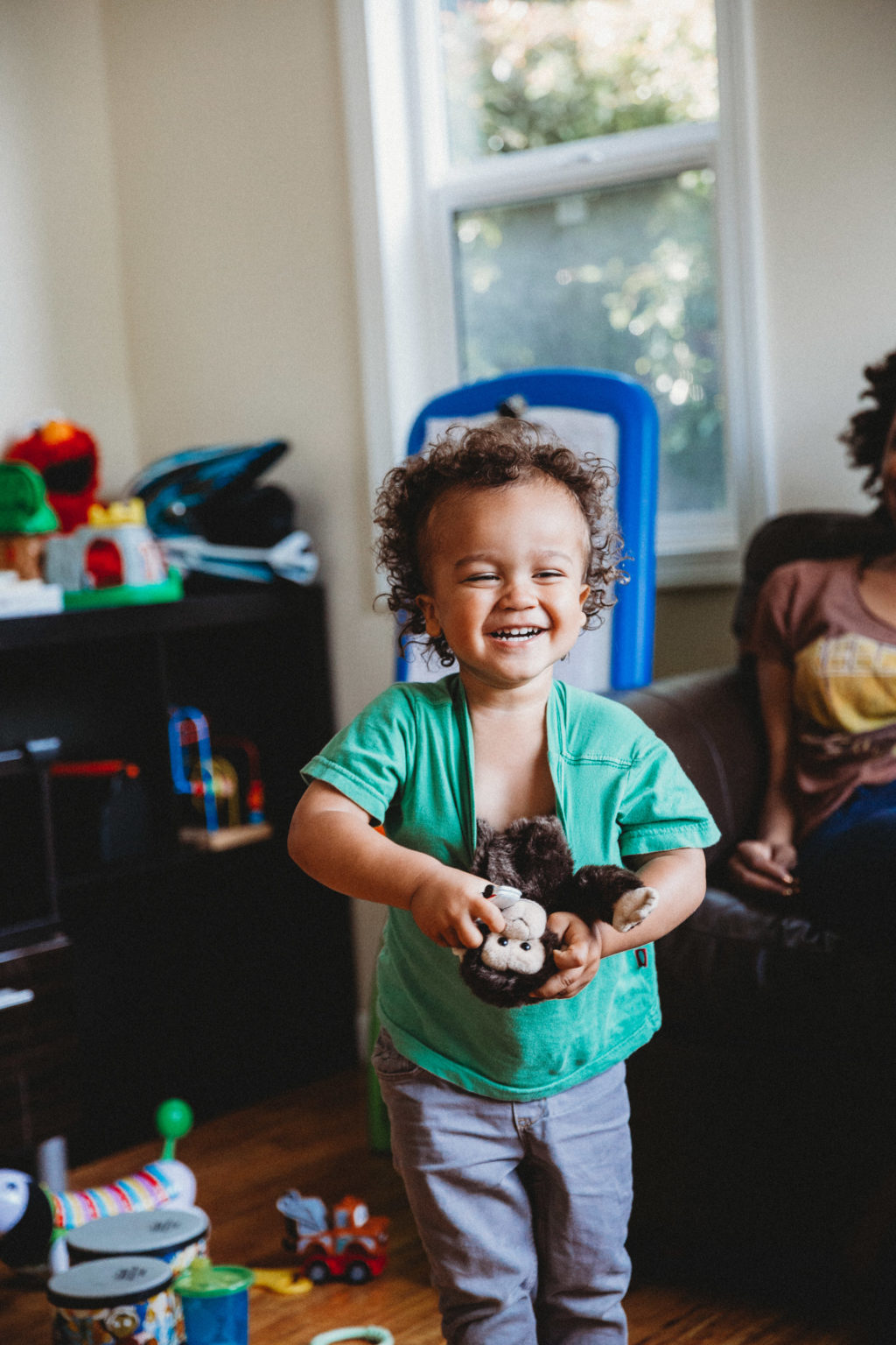 Toddler smiling and pulling stuffed monkey out of shirt