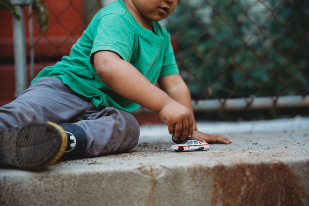 Toddler playing with car on concrete step outside