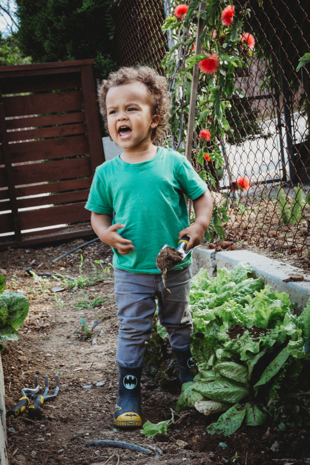 Toddler yelling outside while holding shovel full of dirt