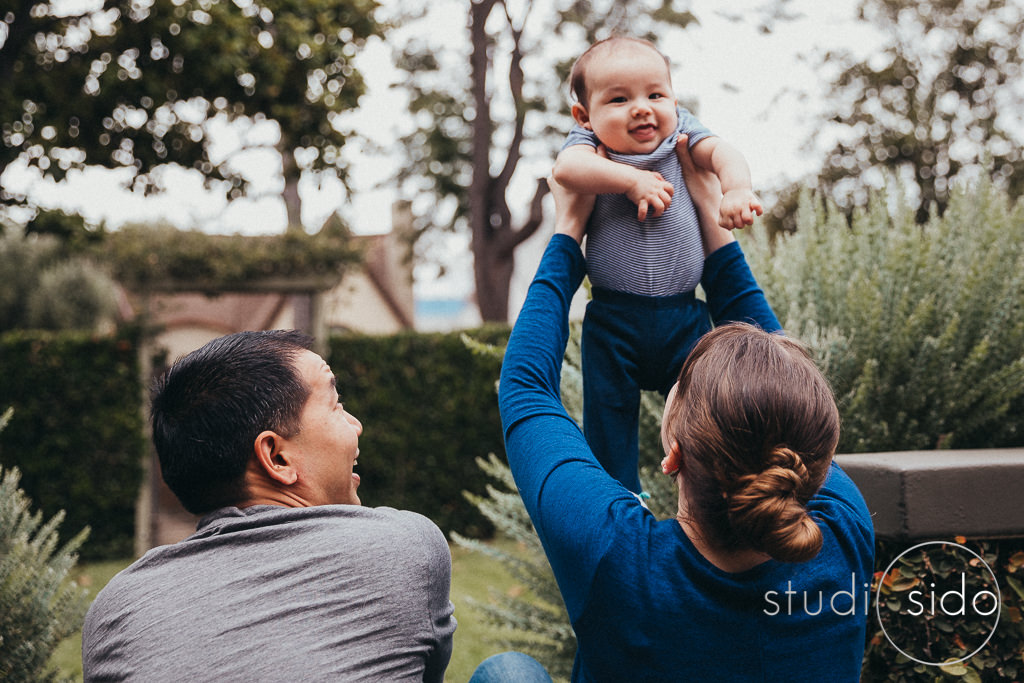 Mom lifting baby up high, sitting next to dad, Los Angeles, CA