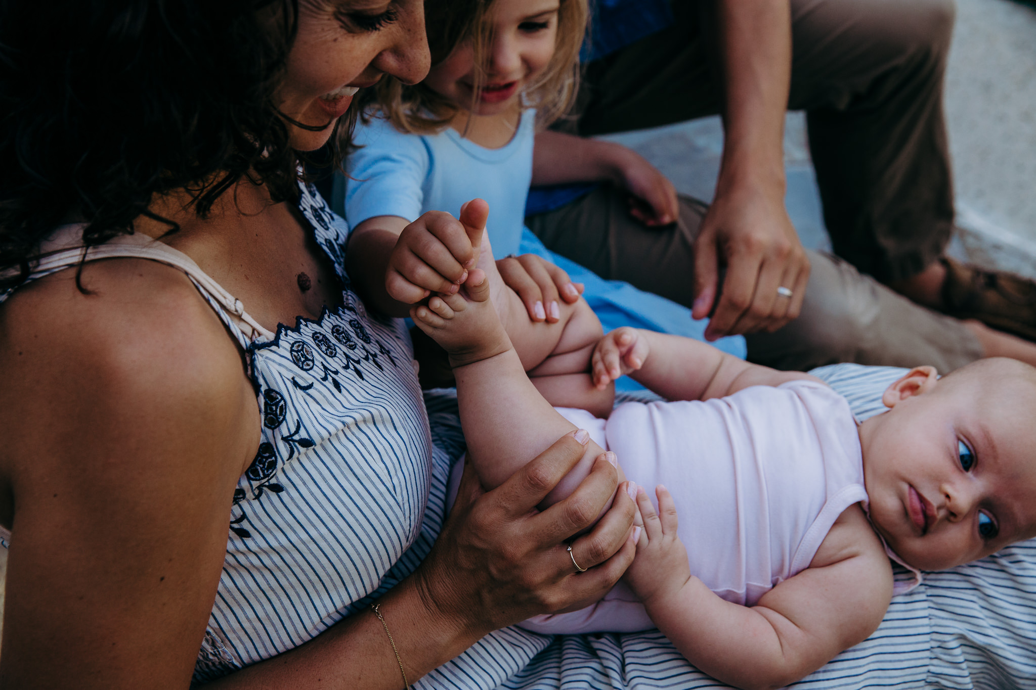 baby lies in her mom's lap while her big sister holds her toes - Atwater Village, CA