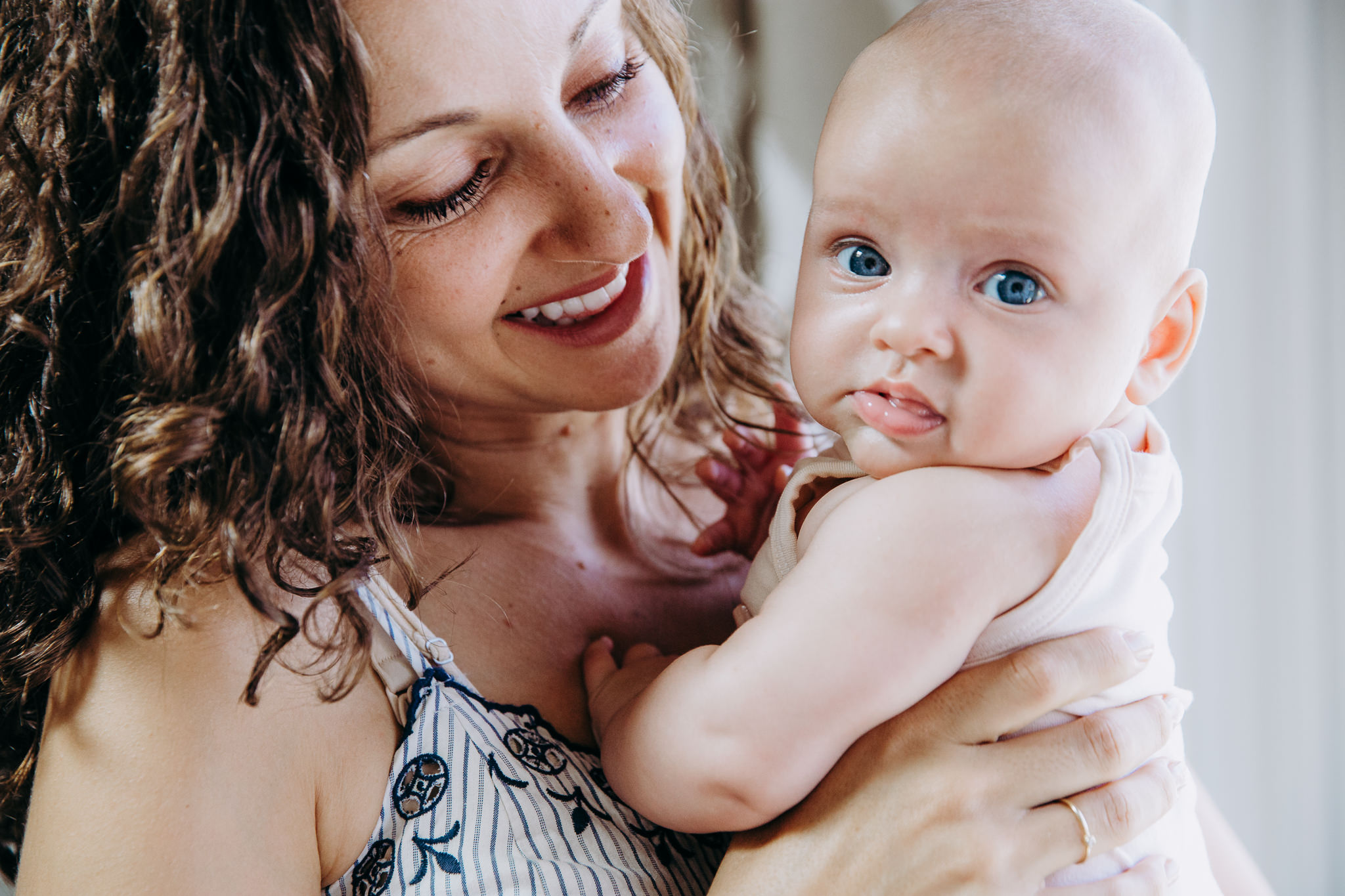 A baby with bright blue eyes in her mother's arms, Atwater Village, CA