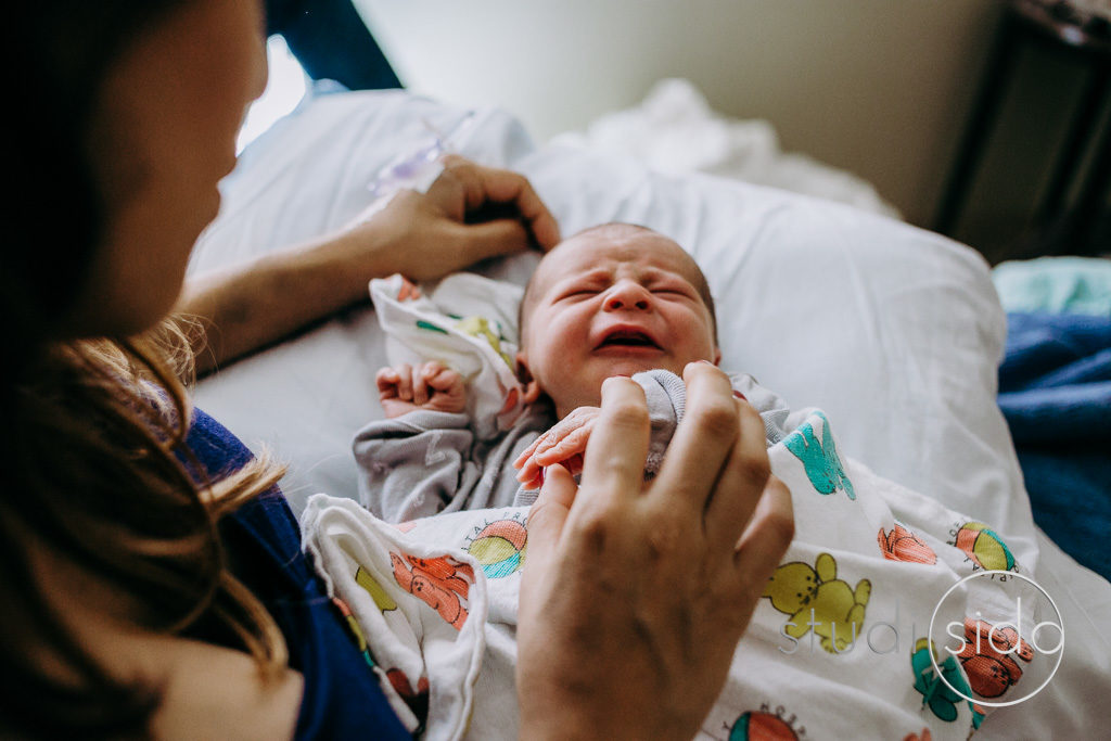 Newborn holds mom's finger