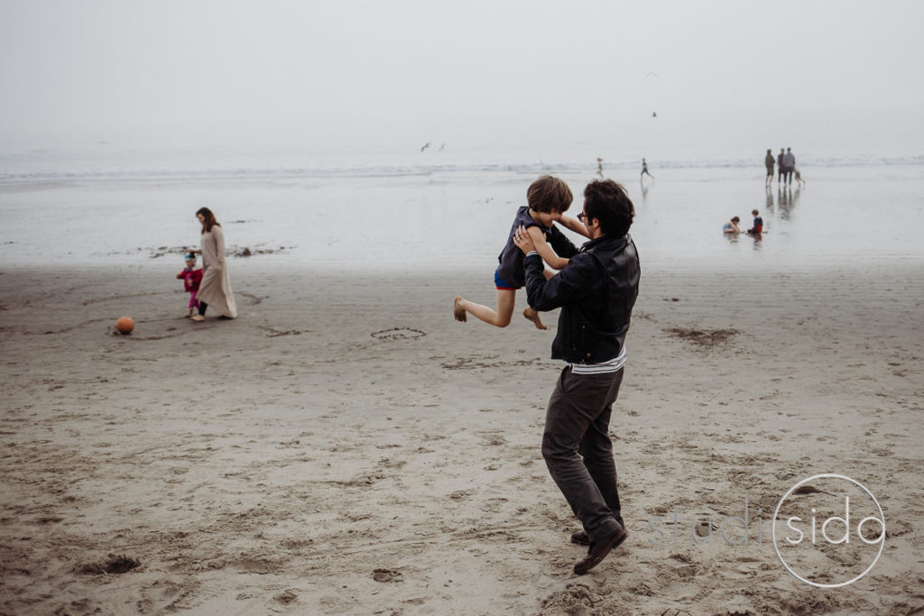 A boy is swung in the air by his dad on the beach in Santa Monica, California.