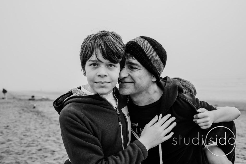 A dad and son cuddle on the beach in Santa Monica, California.