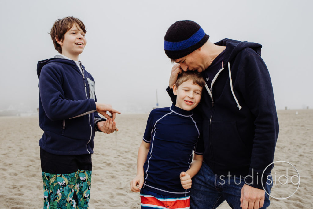 Dad and boys laughing on a Santa Monica beach.