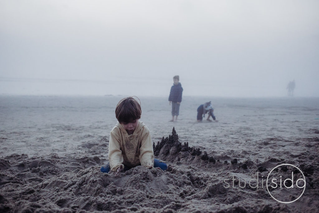 A boy builds a sand castle on a foggy beach in Santa Monica, California.