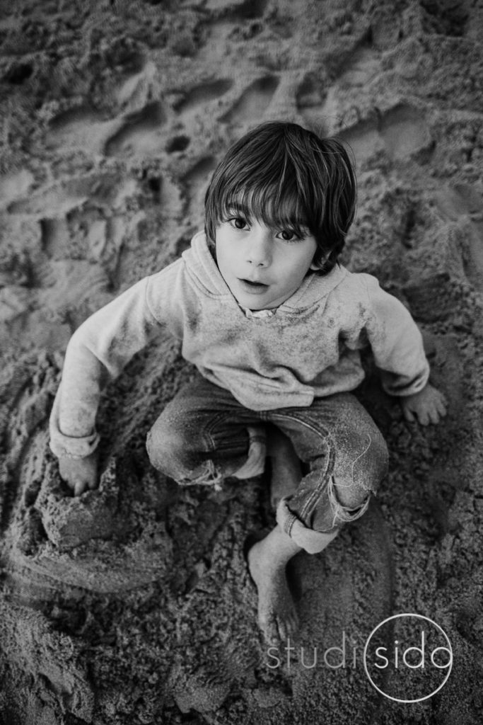 A boy sits in the sand on the beach in Santa Monica, California.