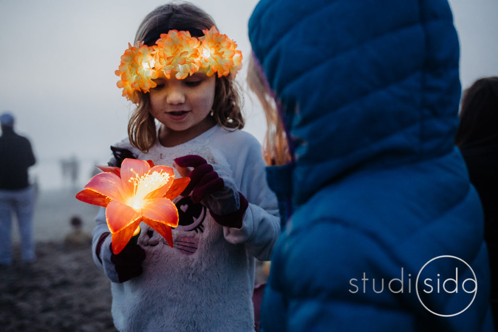 A girl plays with a lit up flower on a Santa Monica beach.