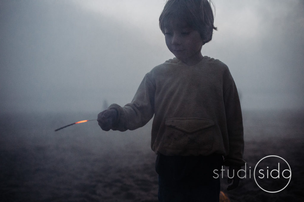 A boy holds a sparkler as it goes out on the beach in Santa Monica, CA.