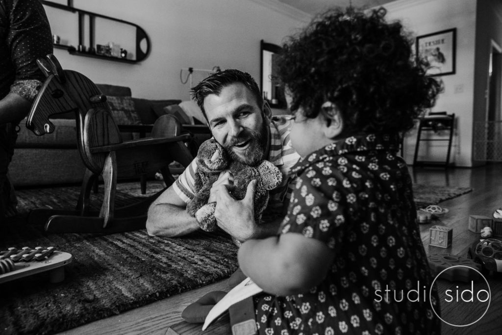 A dad holds a bunny and looks at his son in West Hollywood, California. B&W photograph.