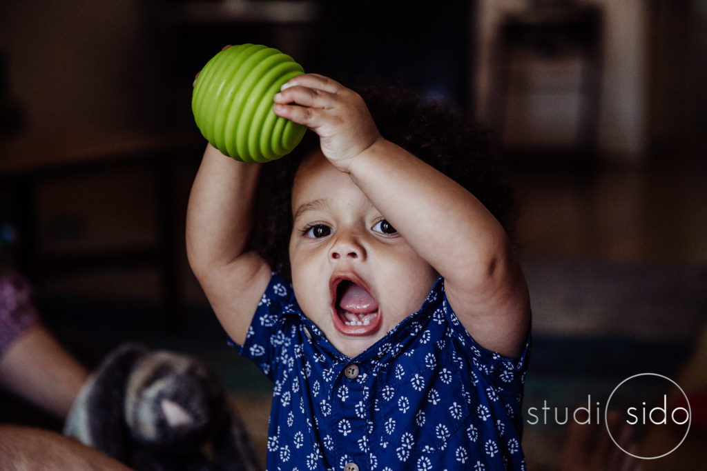 A toddler happily holding a ball over his head in West Hollywood, CA.