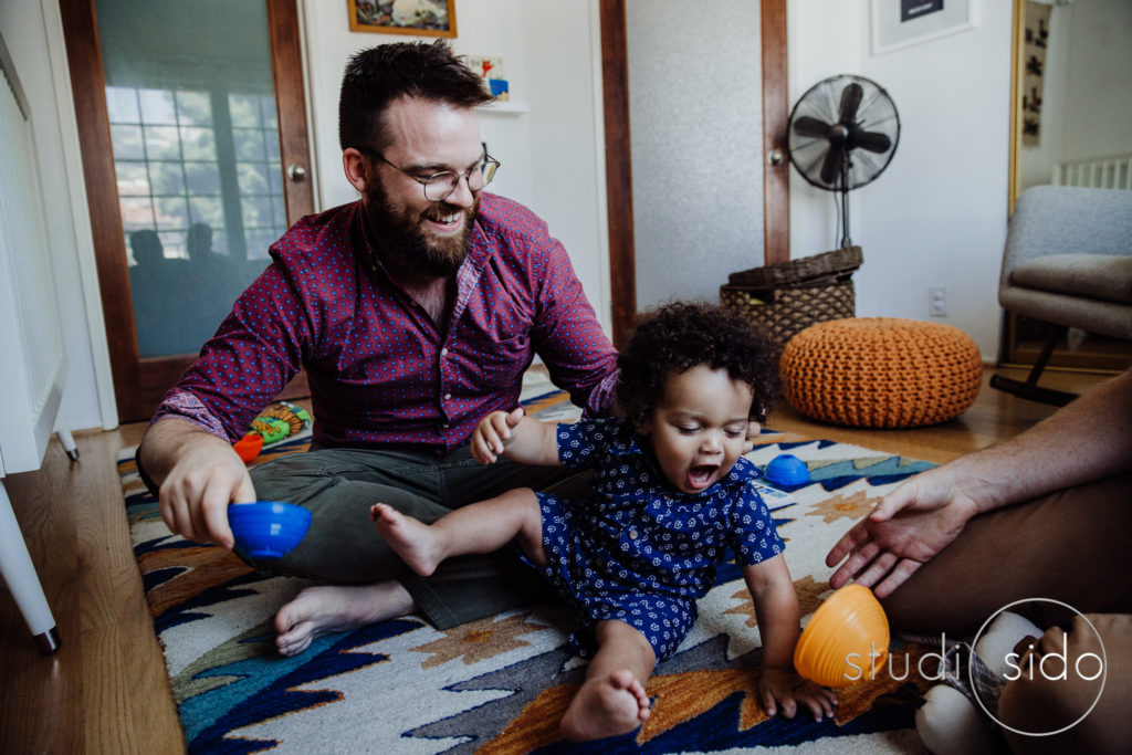 A boy plays with his dads and a ball in West Hollywood, CA.