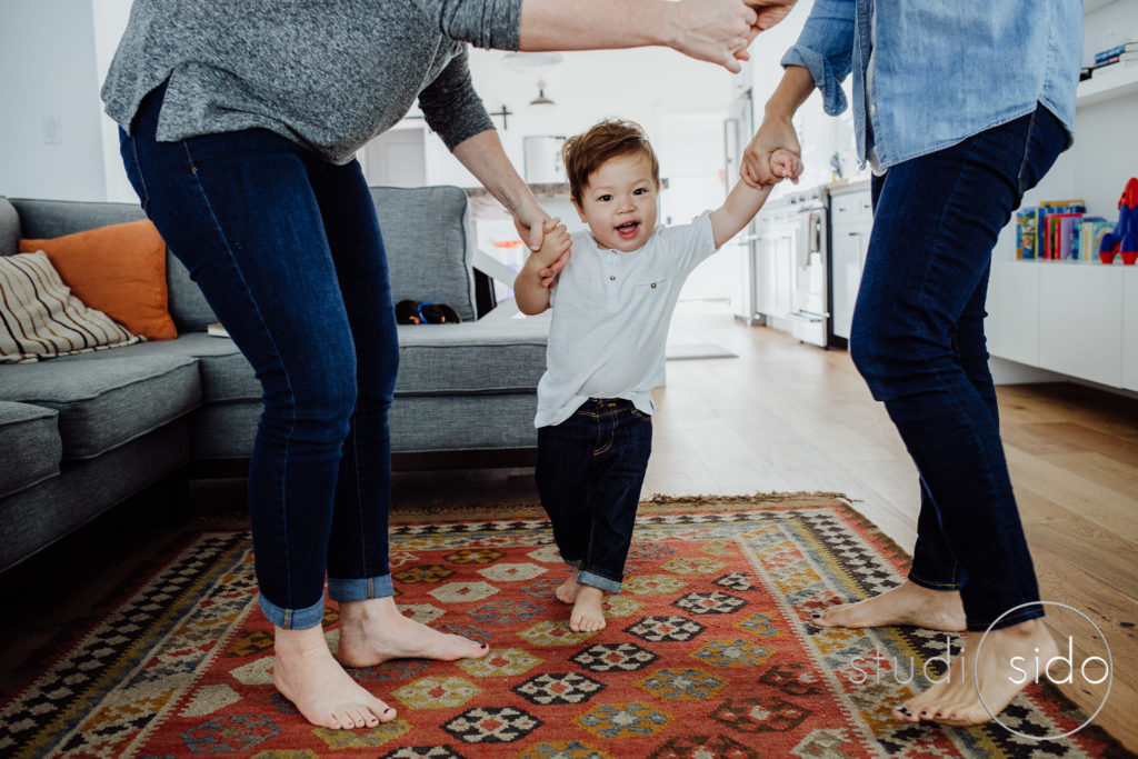 A toddler plays ring around the rosie with his moms