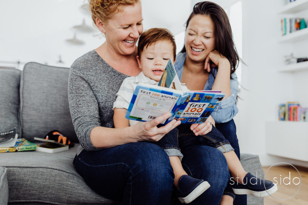 Moms read with their son in their home in Los Angeles, CA