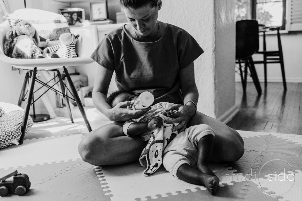 Boy takes a bottle in his mom's lap in Silver Lake, Los Angeles, CA