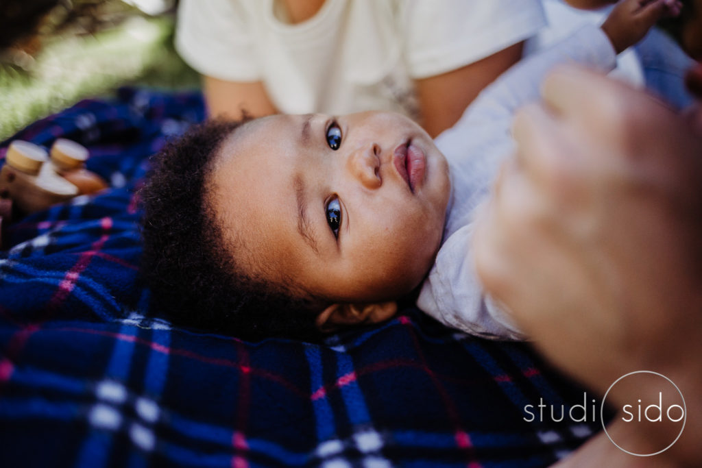 Little boy lies on a blanket with his moms outside their home in Los Angeles, CA