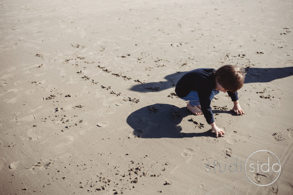 Child Drawing In Sand With Footsteps Behind him