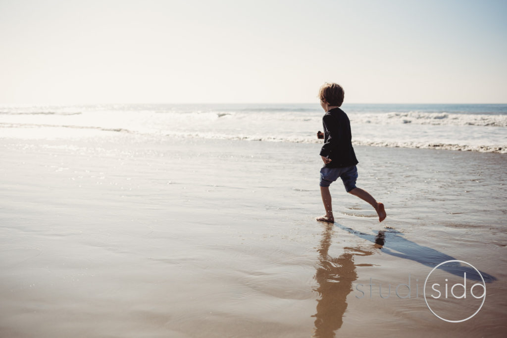 Child Running Along Shore With Occean in Background