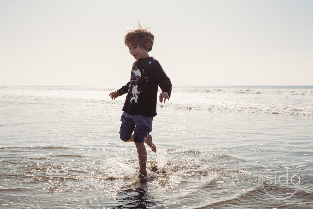 Child Splashing In Water On Beach in California