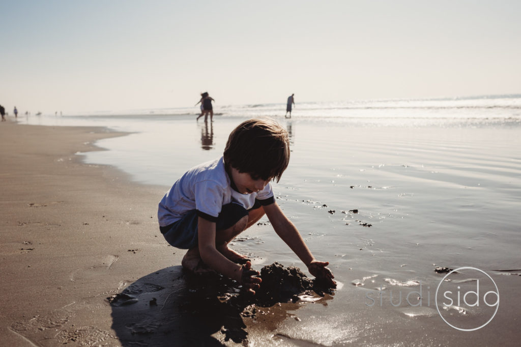 Child Scooping Up Sand on Beach