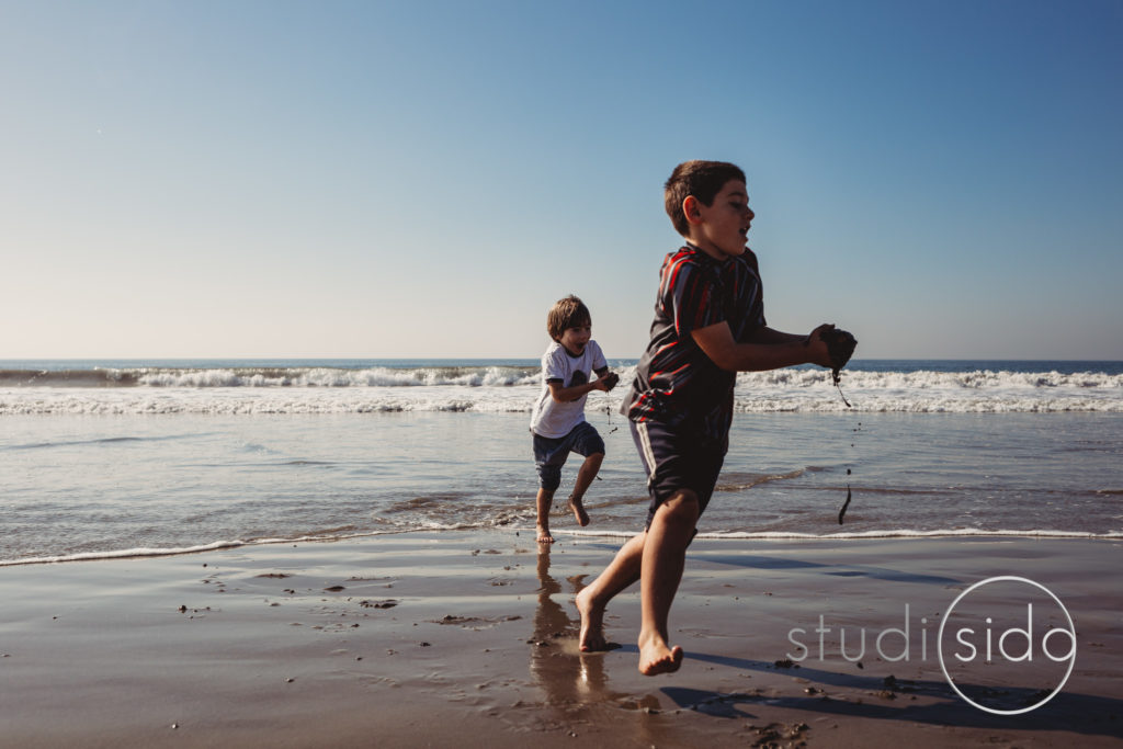 Two Kids Running Through Water and Sand on Beach