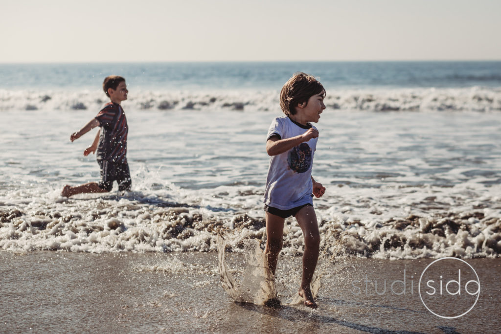 Two Kids Playing Happily in Water on Beach