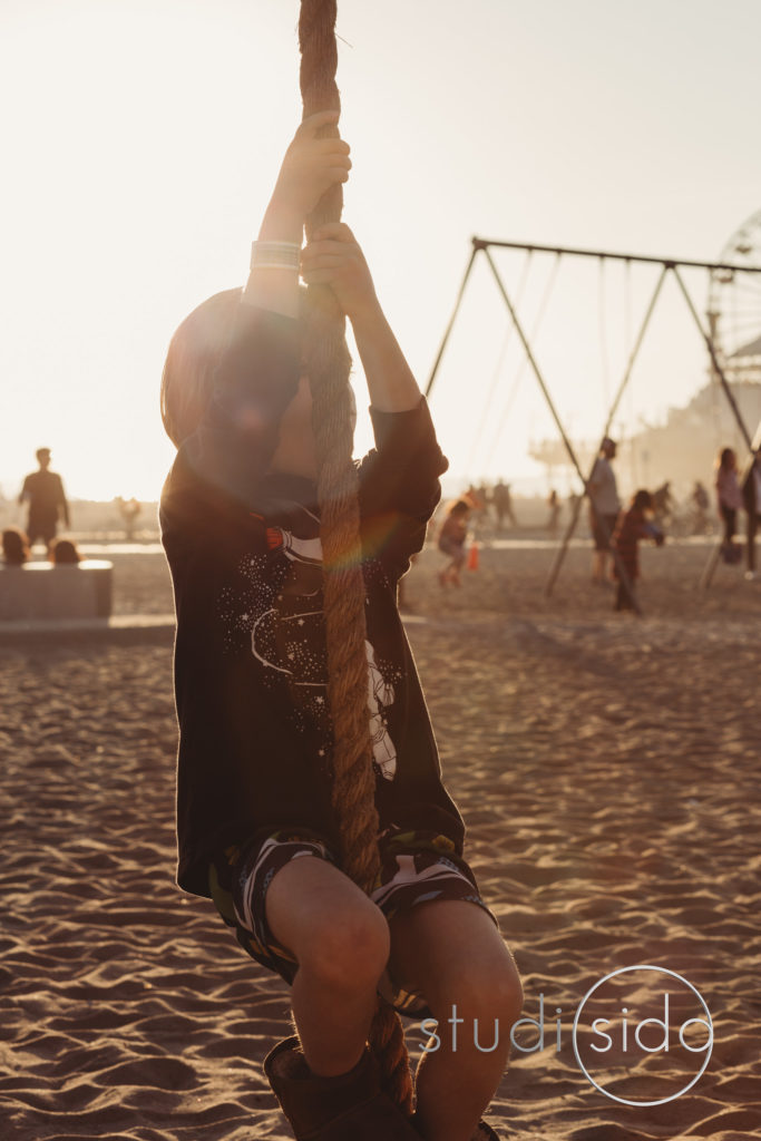 Young child climbing rope on beach