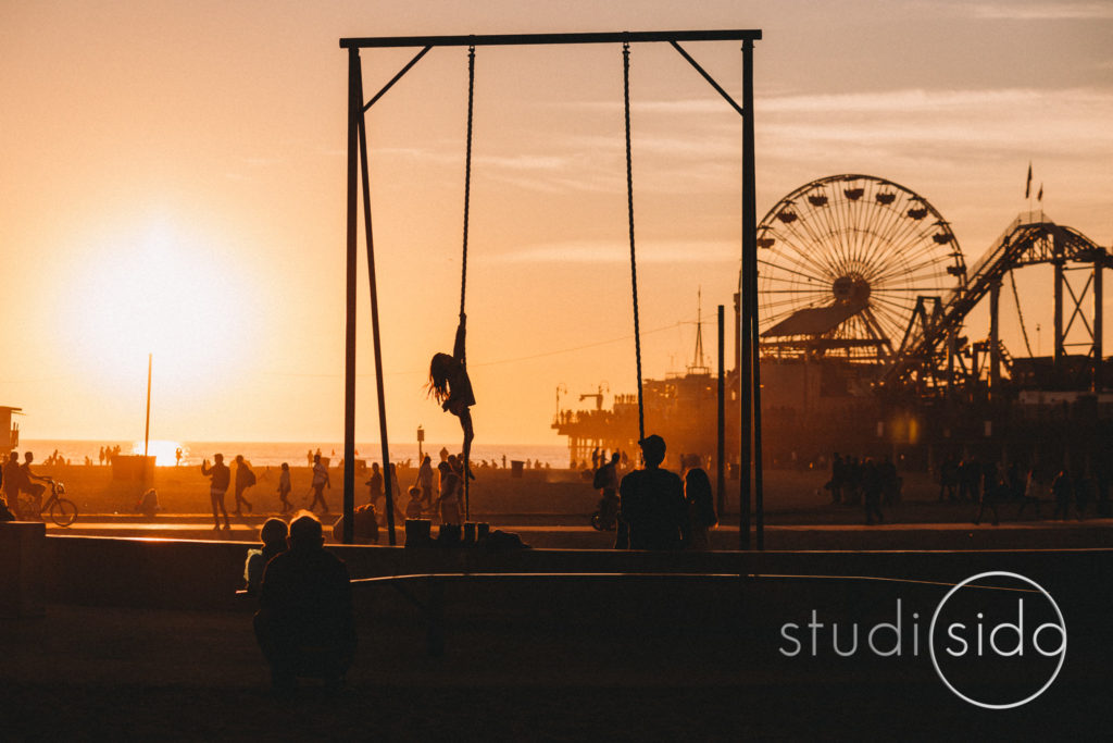 Child climbing on swing set with Ferris wheel in background on beach