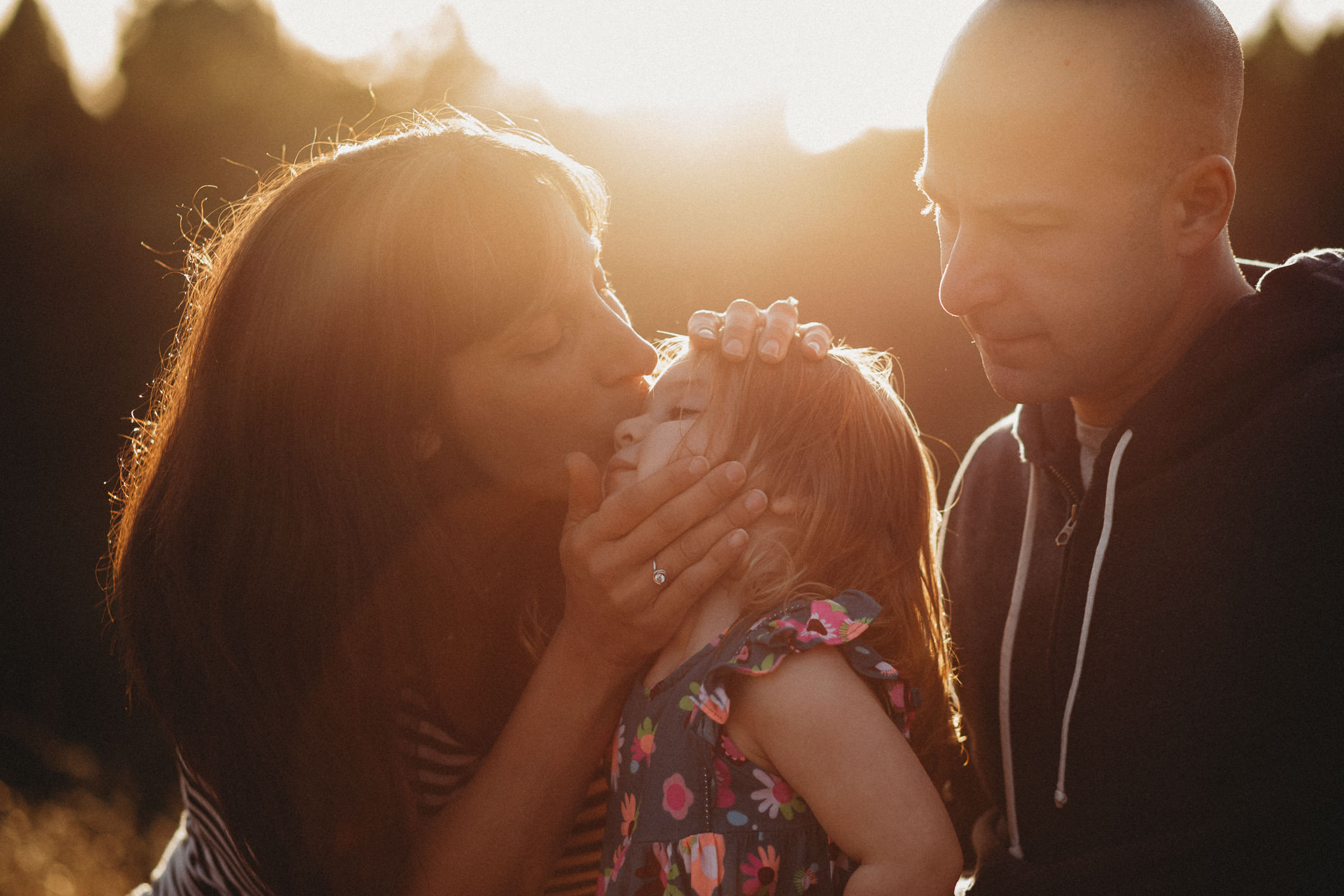 Family sits together, mother kisses her daughter