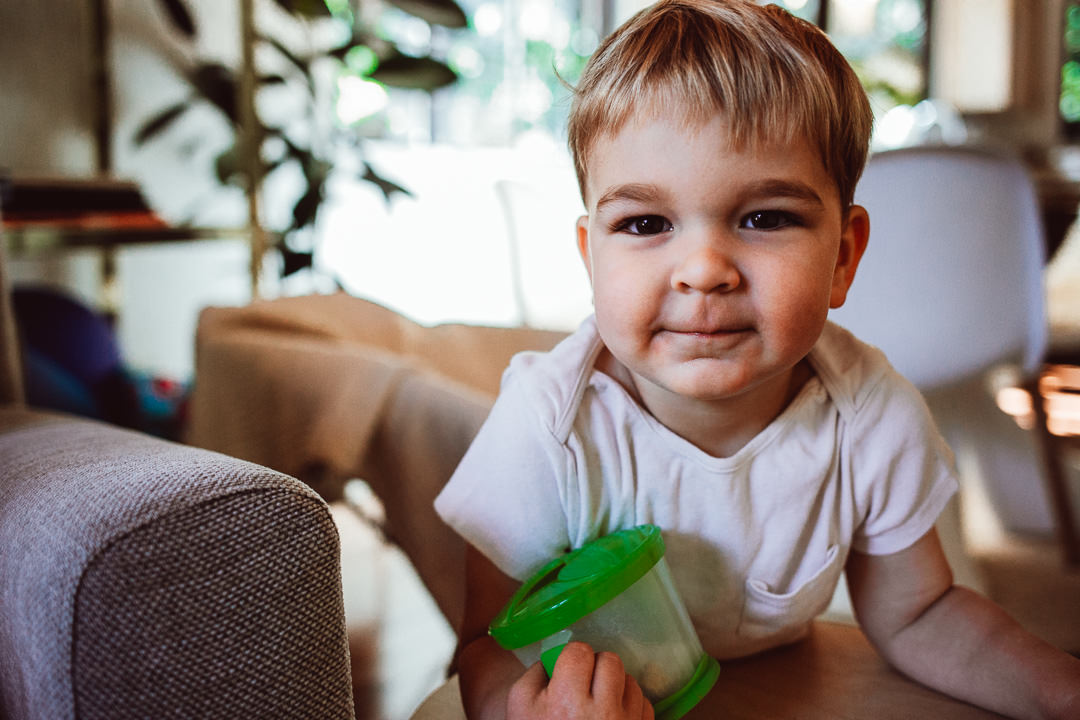 Toddler Son Holding Snack And Smirking At Camera