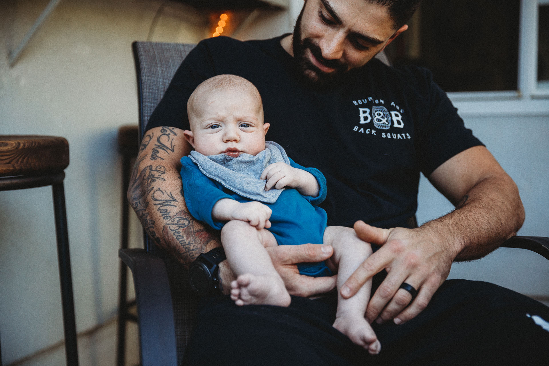 Baby boy looks serious in dad's arms