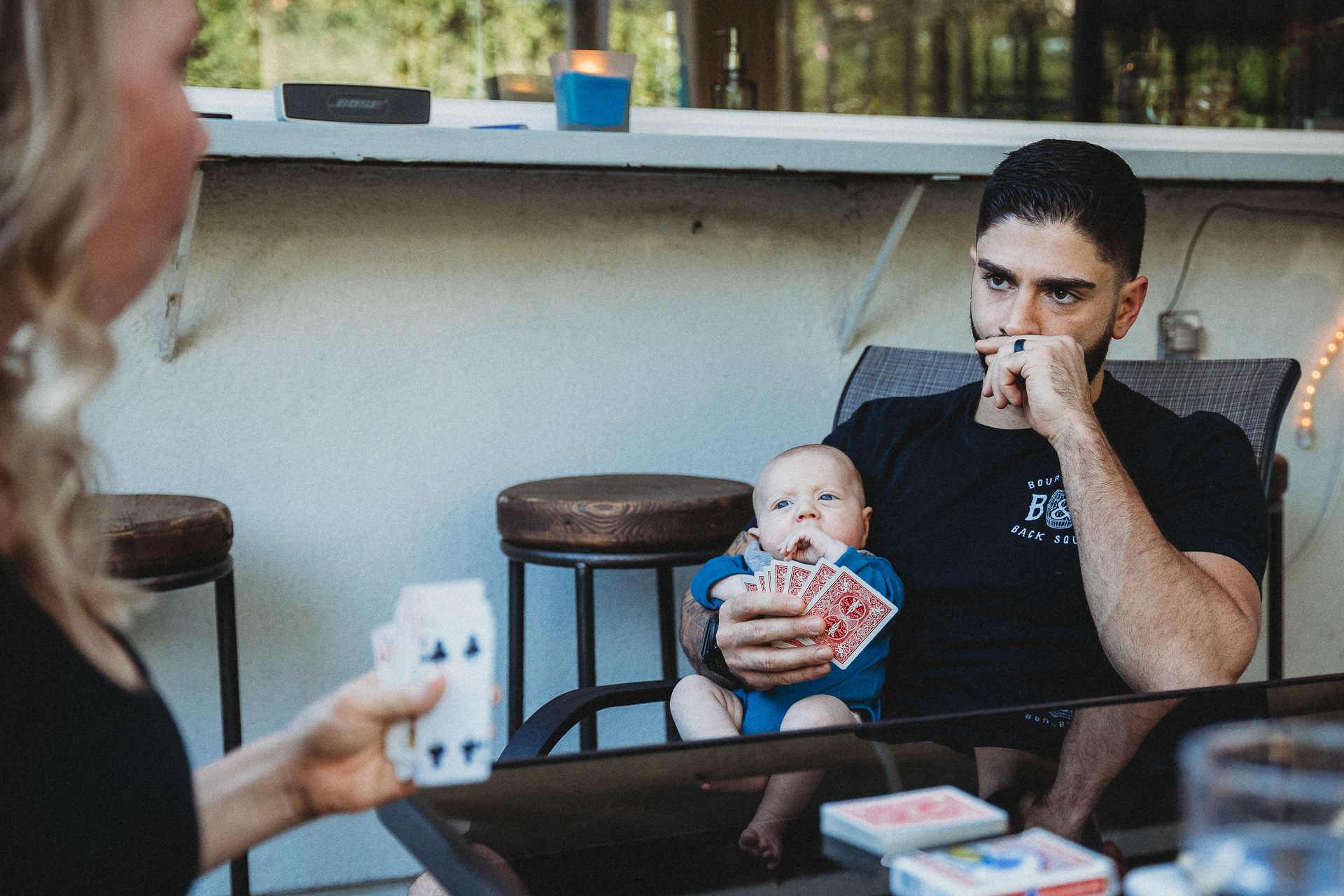 Dad plays a card game with his baby in his arms, Los Angeles, CA