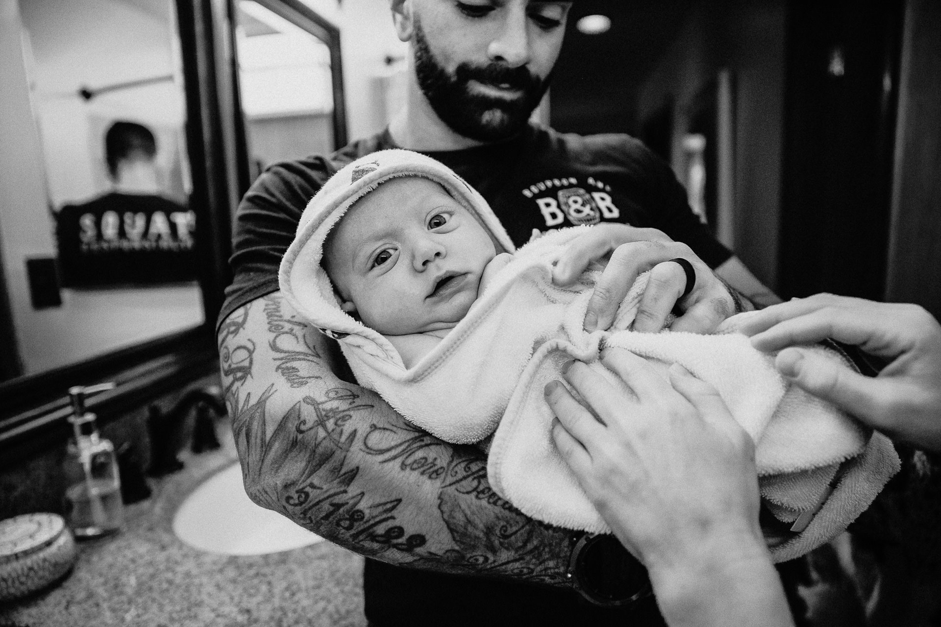 A dad holds his baby wrapped in a blanket after a bath