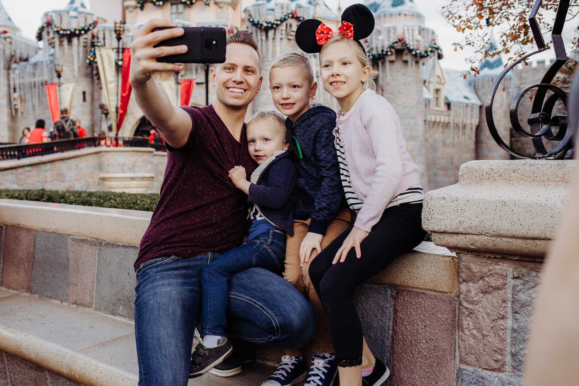 Photograph of Dad and kids taking a selfie in front of the castle at Disneyland in Anaheim, CA