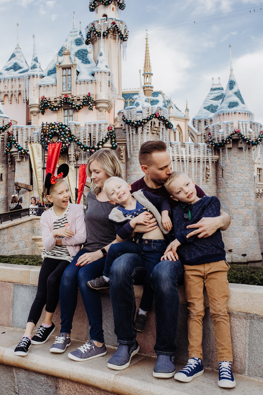 A family cuddles in front of the castle at Disneyland