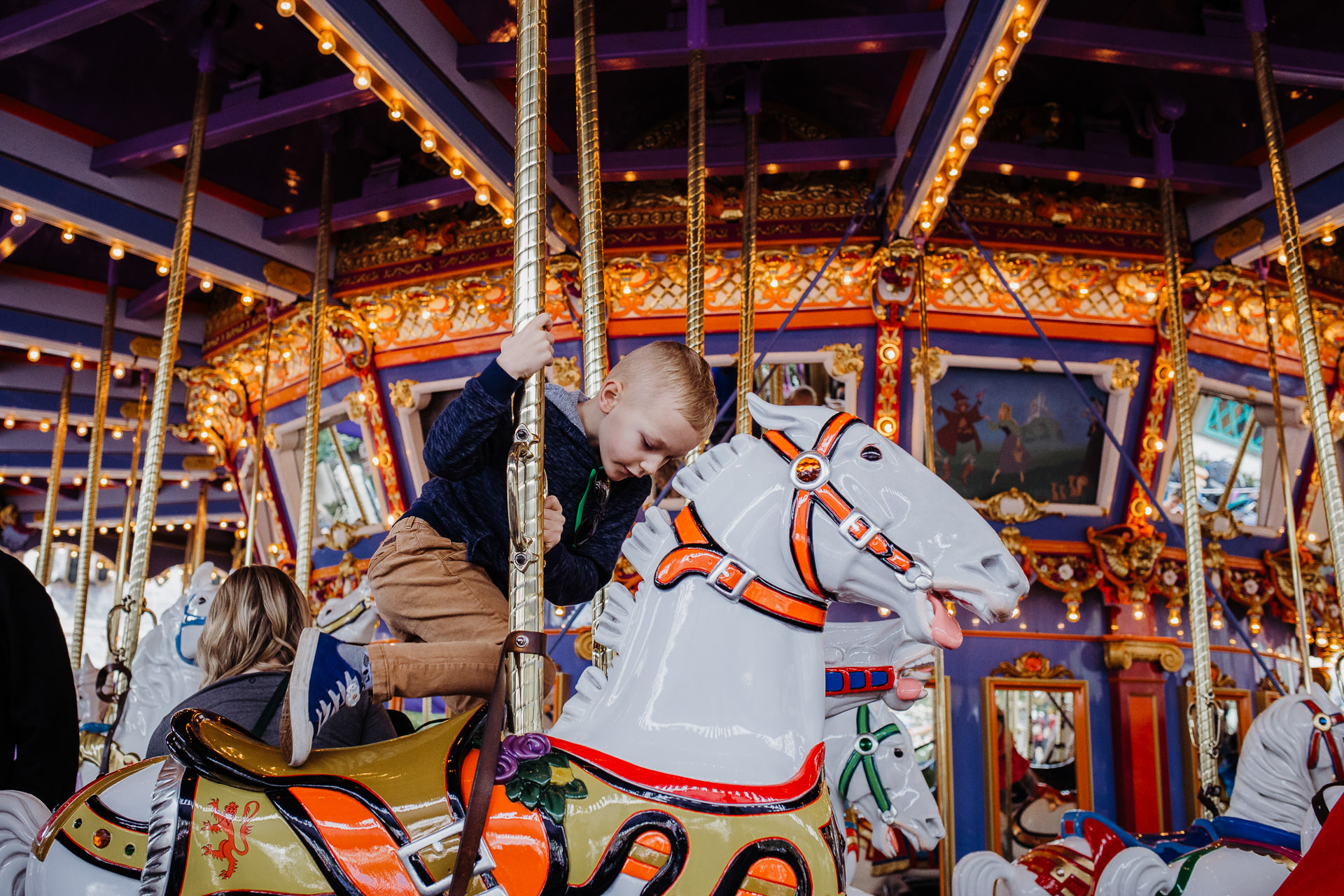 Boy climbs off a carousel horse at Disneyland