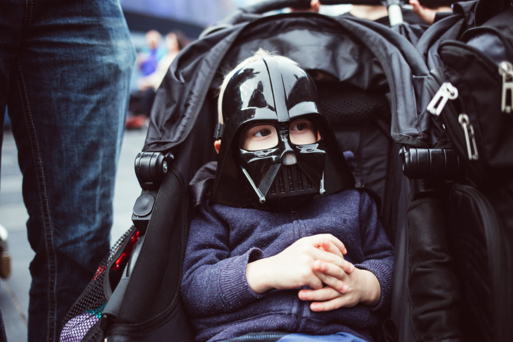 A little boy wears a Darth Vader mask while in his stroller at Disneyland