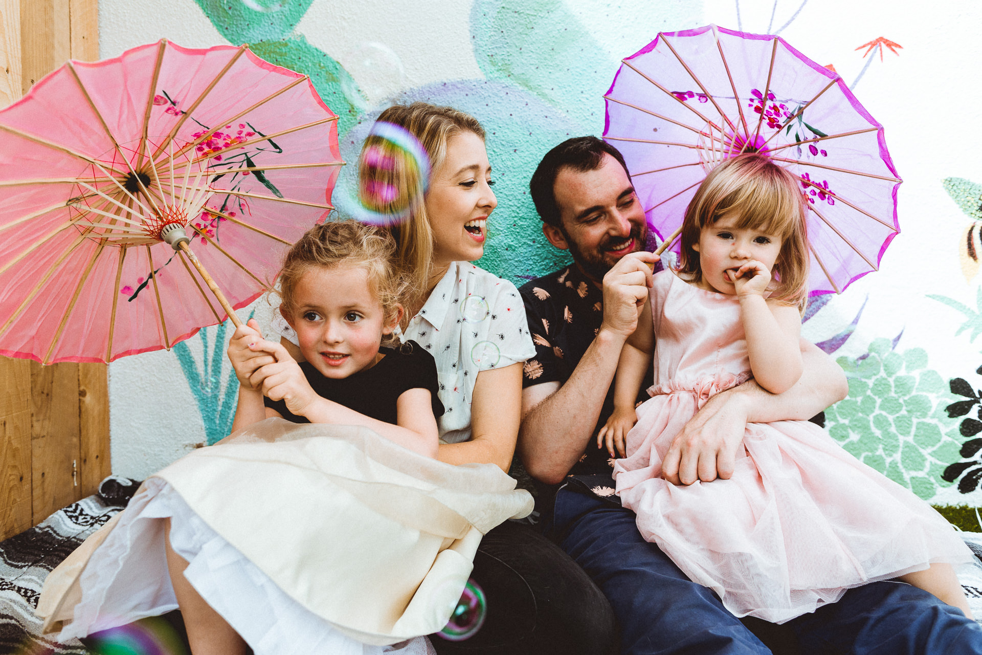 Family laughs together, Girls have parasols at The Great Escape Club in Atwater Village, Los Angeles, CA 