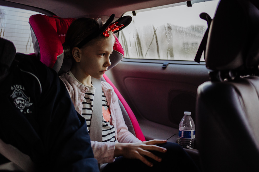 Girl sits in car wearing Minnie Mouse ears, on the way to Disneyland