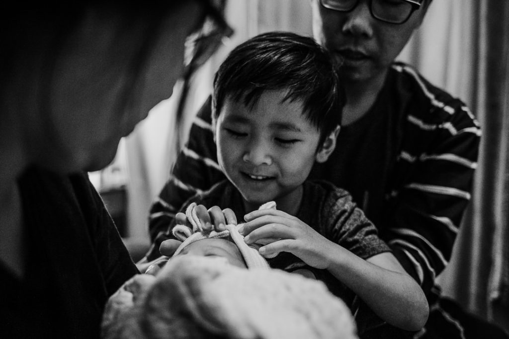 Young boy looks down at his newborn baby sister.