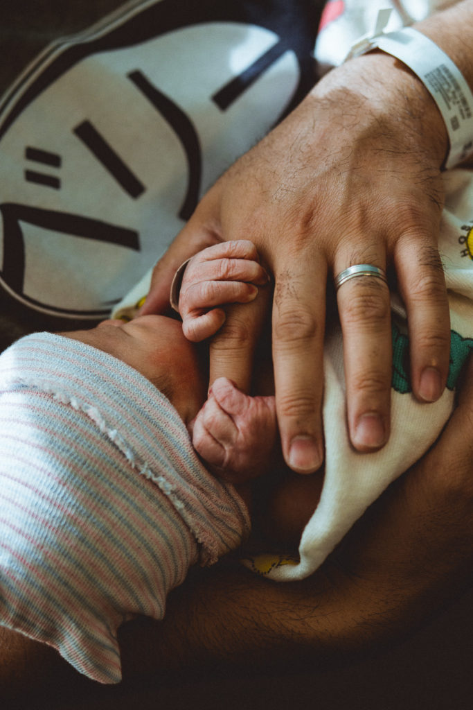 A newborn hold's his dad's finger