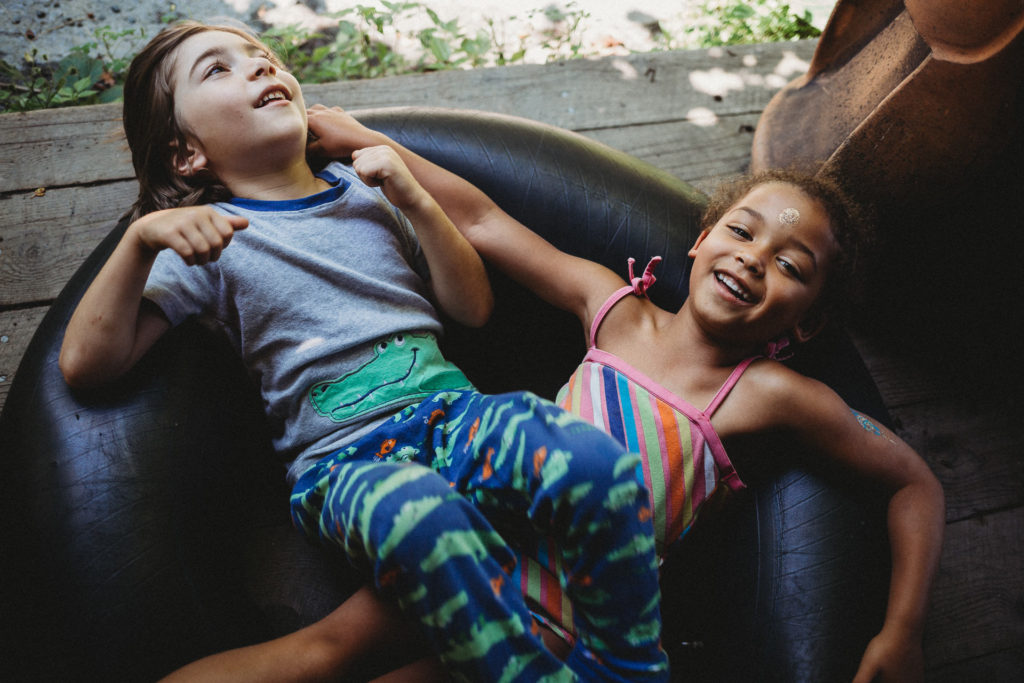 A boy and girl lie across an inner tube