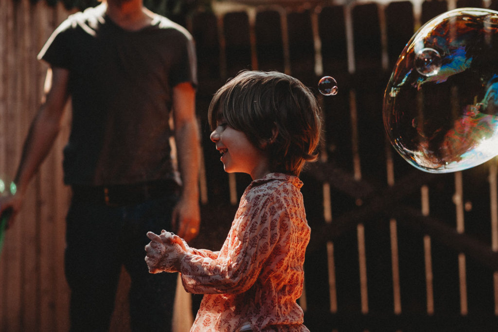 young boy plays with giant bubbles in his yard in Los Angeles