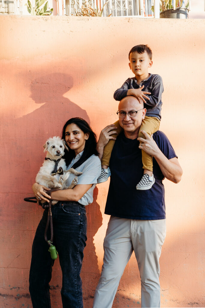 Family with Dog Poses Outside in Front of Peach Wall