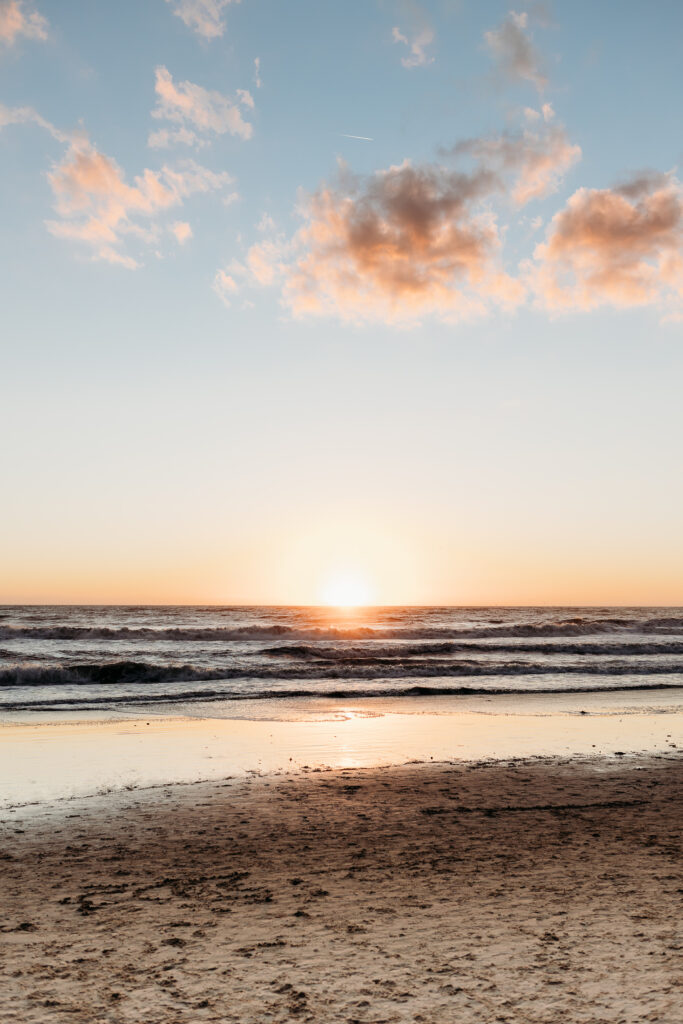 the sky turns pink while the sun sets on the beach in Santa Monica, CA