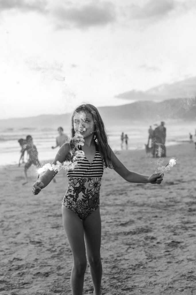 A girl holds sparklers in her hands on the beach, Santa Monica, CA